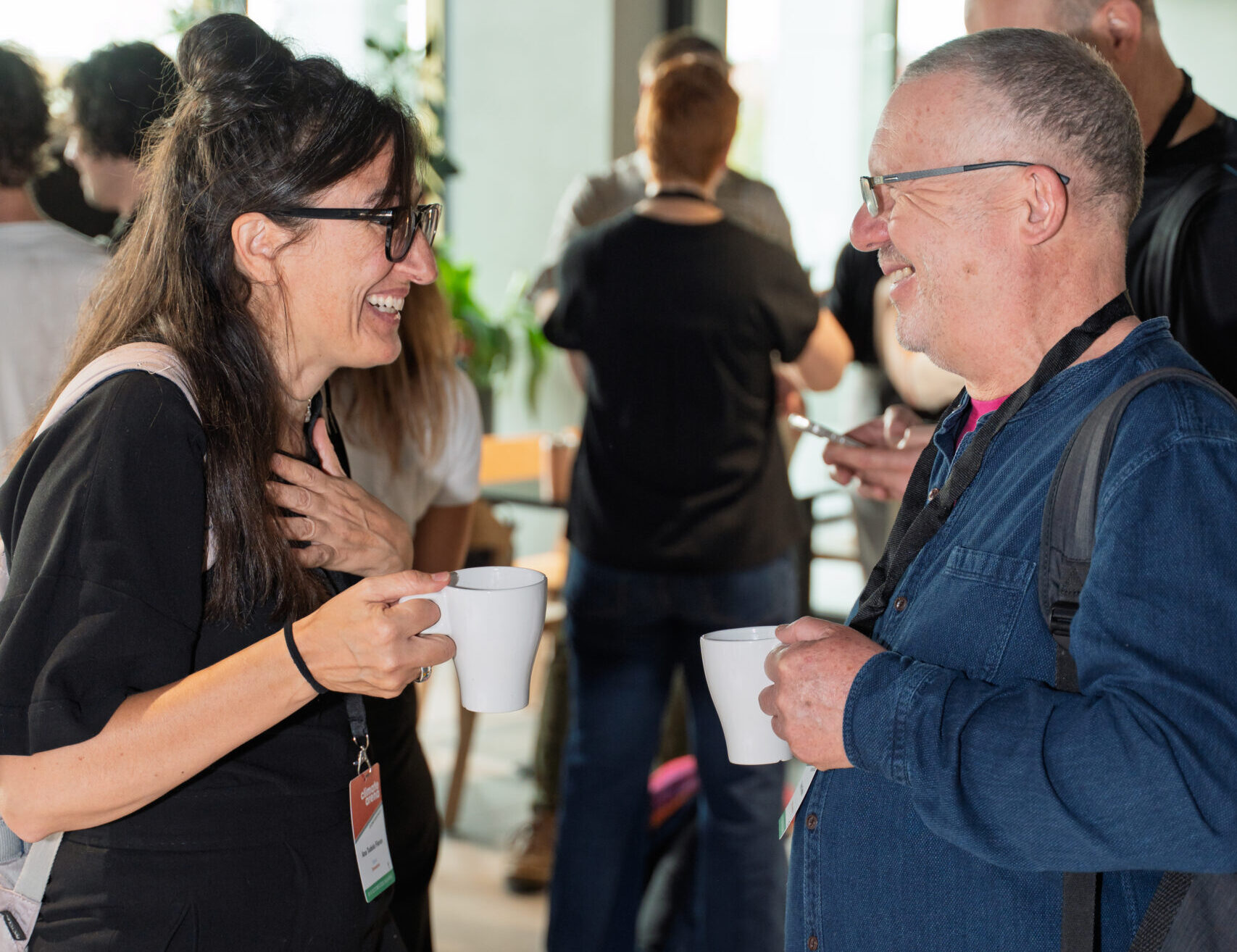 A woman and a man chat excitedly over coffee in a conference networking session.
