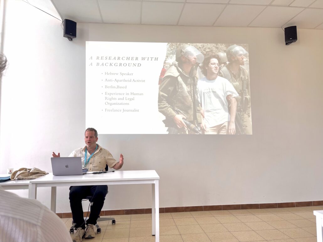 A man gives a presentation, showing a picture of his younger self engaging in activism.